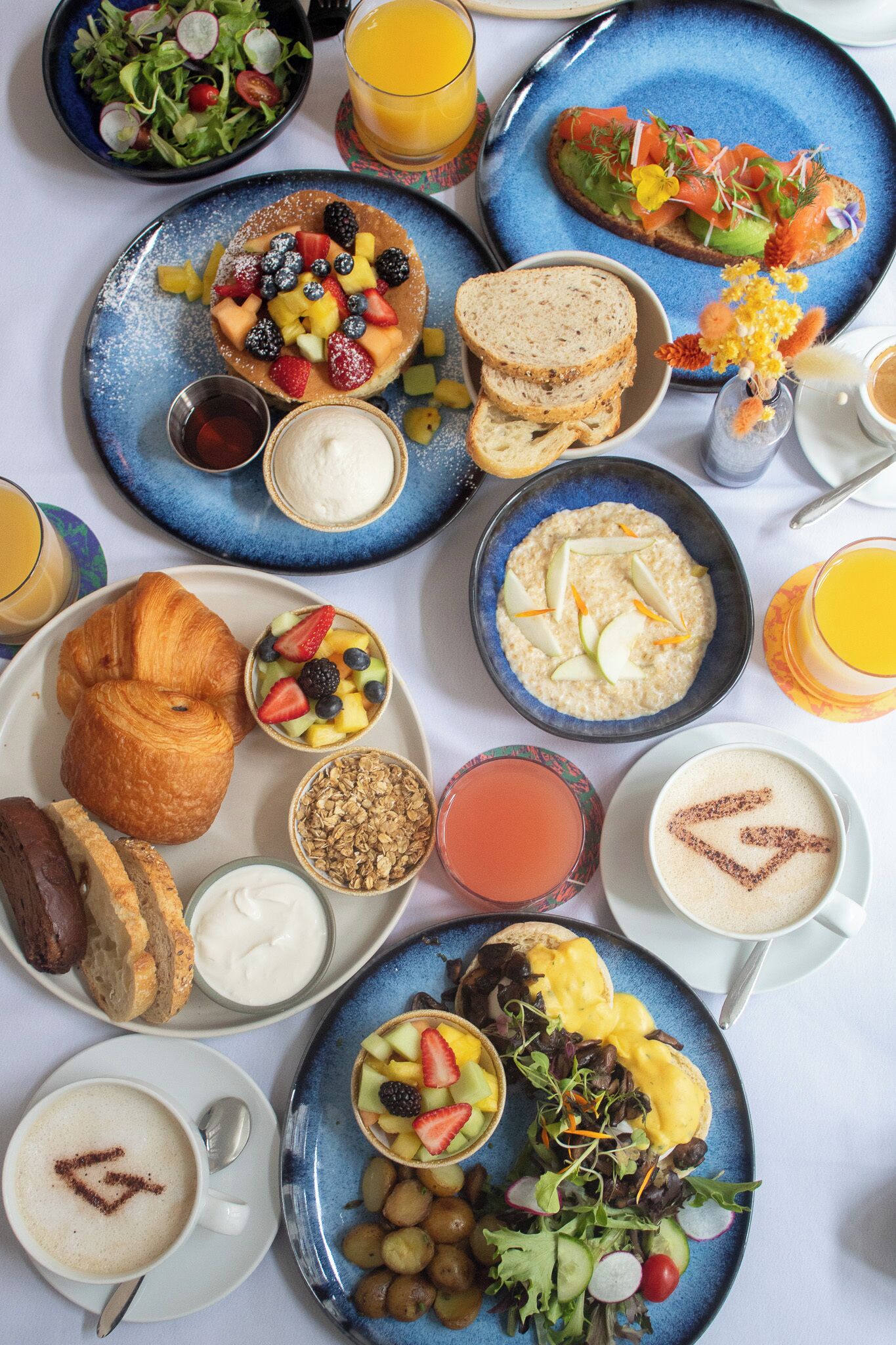 A breakfast spread with various dishes including croissants, fruit, oatmeal, and coffee.