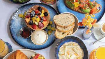 A breakfast spread with various dishes including croissants, fruit, oatmeal, and coffee.