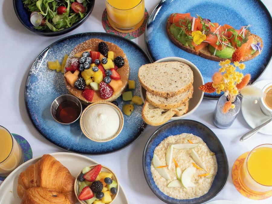 A breakfast spread with various dishes including croissants, fruit, oatmeal, and coffee.