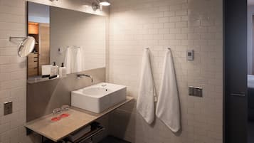 Ein modernes Badezimmer mit einem großen Waschbecken, einem Spiegel und zwei Handtüchern, die an der Wand hängen.