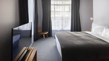 A hotel room with a bed, a TV, a chair, and a desk.