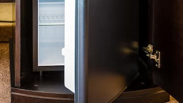A compact refrigerator built into a wooden cabinet with a handle for opening.