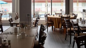 Un restaurante con mesas dispuestas para comer, un balcón con piscina y vistas a un edificio con balcones.
