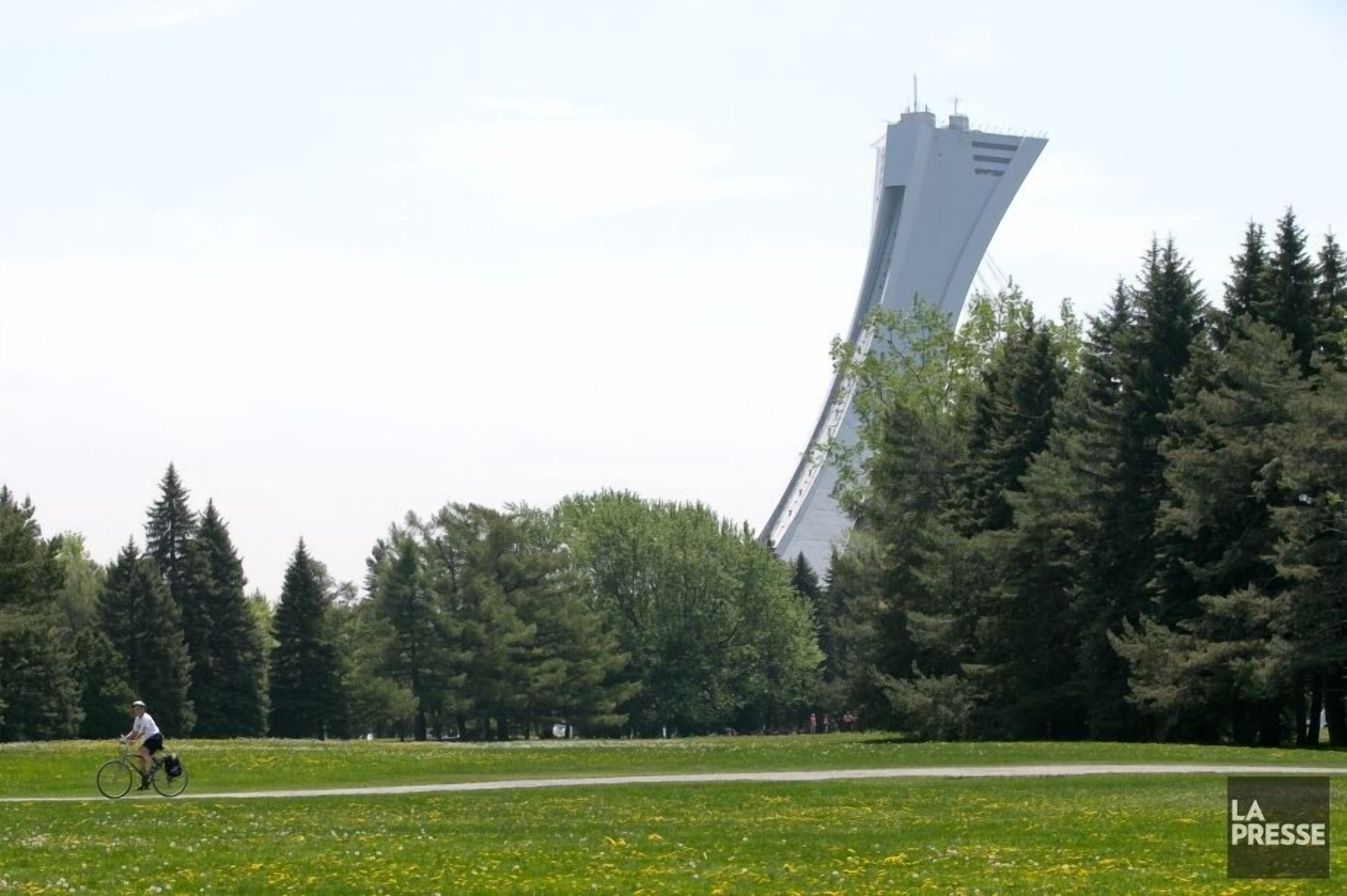 A park with a unique tower structure and a cyclist on a path.