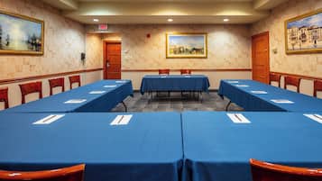 A conference room with a long table, chairs, and paintings on the walls.