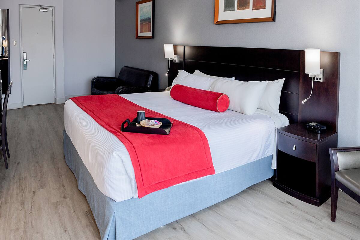 A hotel room with a large bed, a nightstand, a chair, and a door.