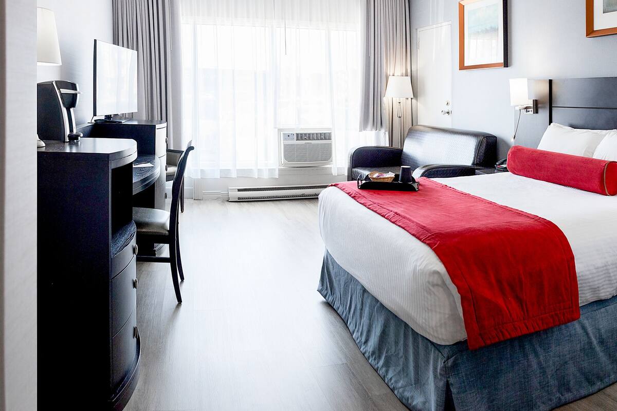 A hotel room with a bed, desk, chair, and a bathroom.
