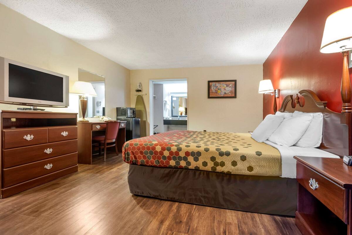 Une chambre d’hôtel équipée d’un lit, d’un bureau, d’une télévision et d’une commode.