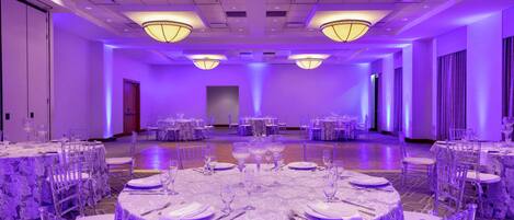 A banquet hall with round tables set for dining, equipped with chairs and table settings.