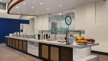A buffet setup with various food items and a sign indicating fruit and yogurt.