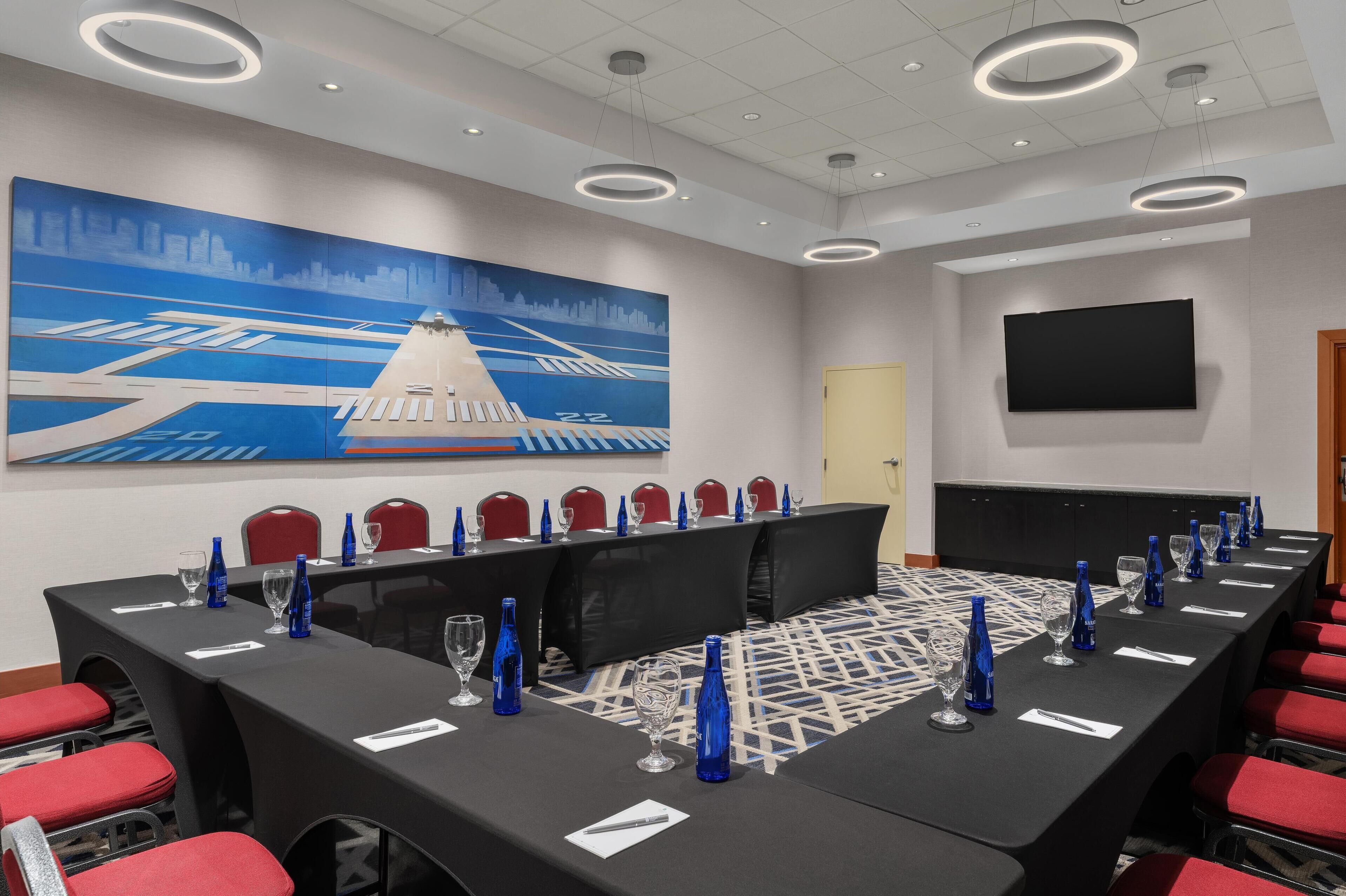 A conference room with a long table, red chairs, and blue water bottles.