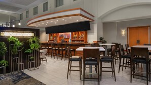 A spacious hotel lobby with a bar area, multiple seating arrangements, and a modern design. - Embassy Suites Boston Logan Airport (Boston)