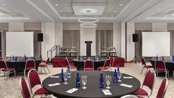 A conference room with round tables, red chairs, and a podium.