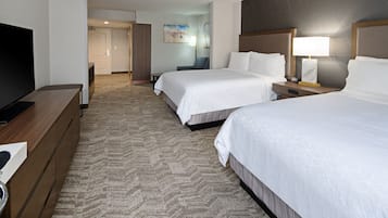 A hotel room with two beds, a TV, a desk, and a carpeted floor.