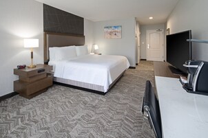 A hotel room with a bed, bedside tables, a TV, and a desk.