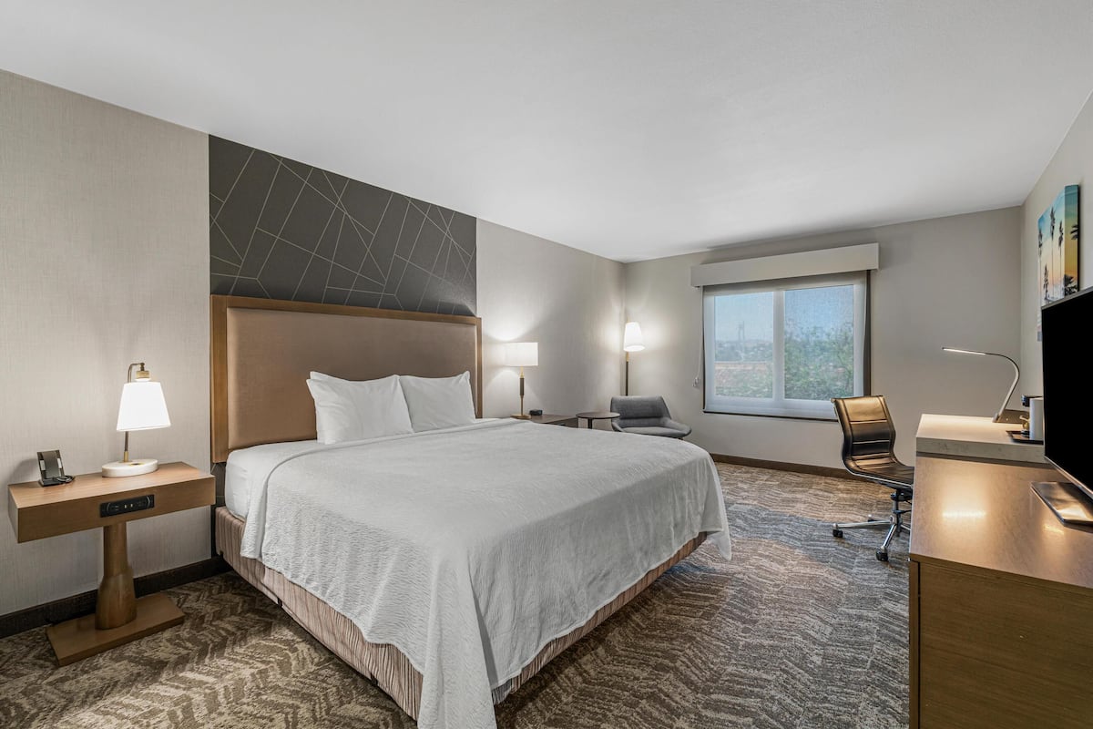 Habitación de hotel con una cama grande, un escritorio, una silla y una ventana.