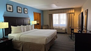 A hotel room with a large bed, a desk, a TV, and a window with curtains. - Wingate by Wyndham Lubbock TX South (Lubbock)