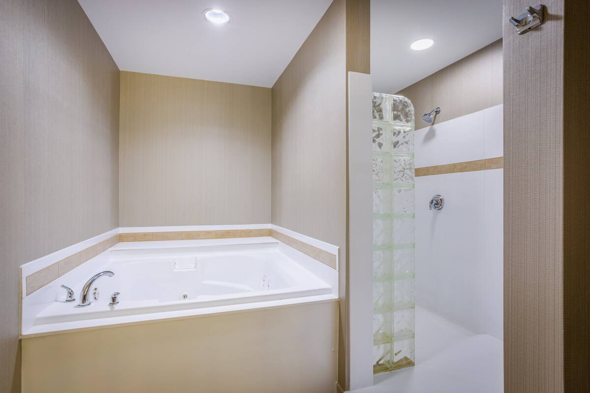 Ein modernes Badezimmer mit einer freistehenden Badewanne, einer Dusche mit Glaswand und Einbaustrahler.