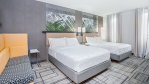 A hotel room with two beds, a sofa, a small table, and a large abstract painting on the wall. - Holiday Inn Lafayette-City Centre by IHG (Lafayette)