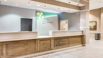 A reception area with a modern design, featuring a reception desk, a wall-mounted information board, and a wooden panel accent.