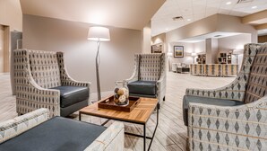 A modern lobby with patterned armchairs, a wooden coffee table, and a floor lamp. - Holiday Inn Lafayette-City Centre by IHG (Lafayette)