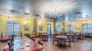 A spacious dining area with multiple tables and chairs, ceiling lights, and framed pictures on the walls. - Holiday Inn Lafayette-City Centre by IHG (Lafayette)