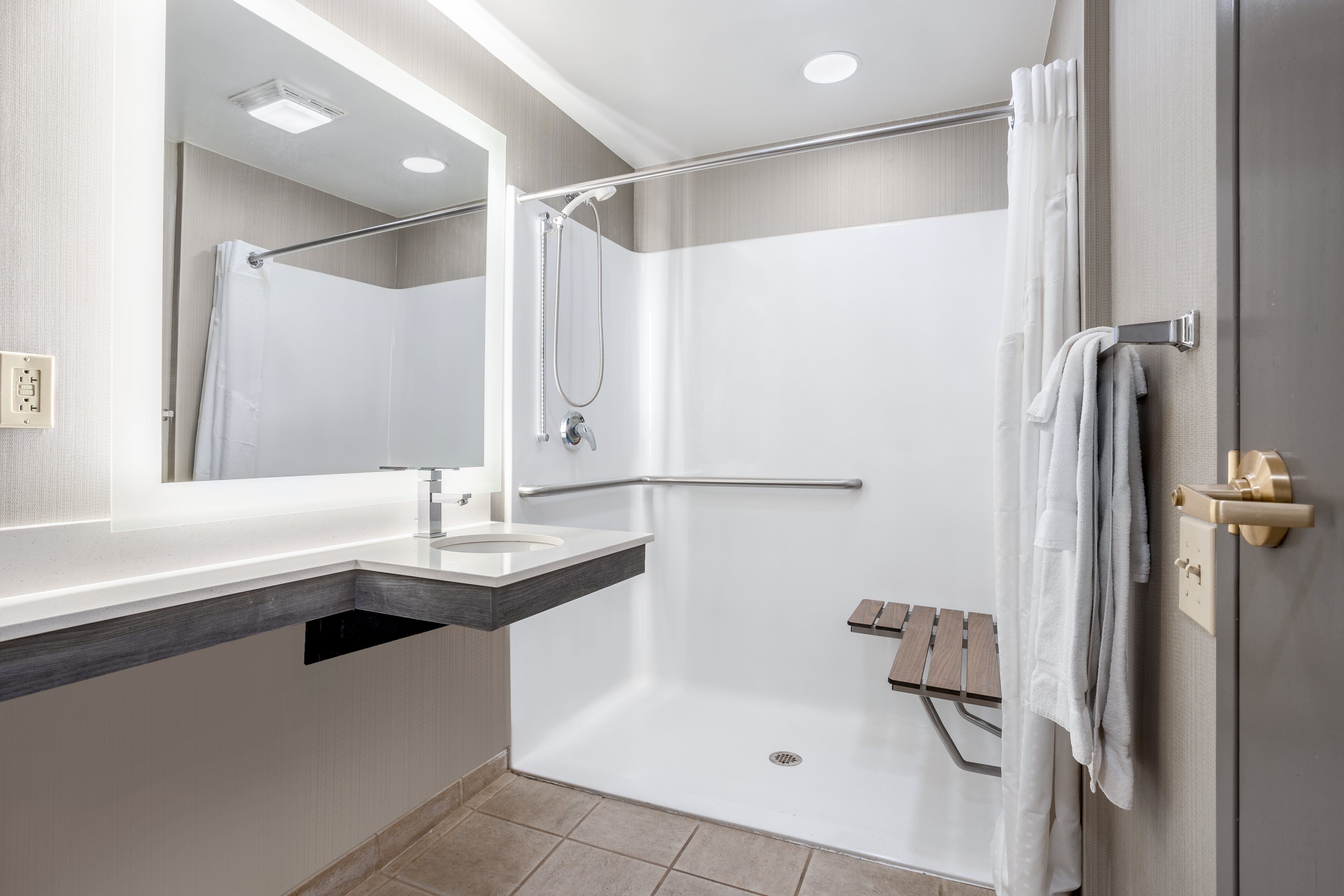 A modern bathroom with a shower, a sink, and a towel rack.