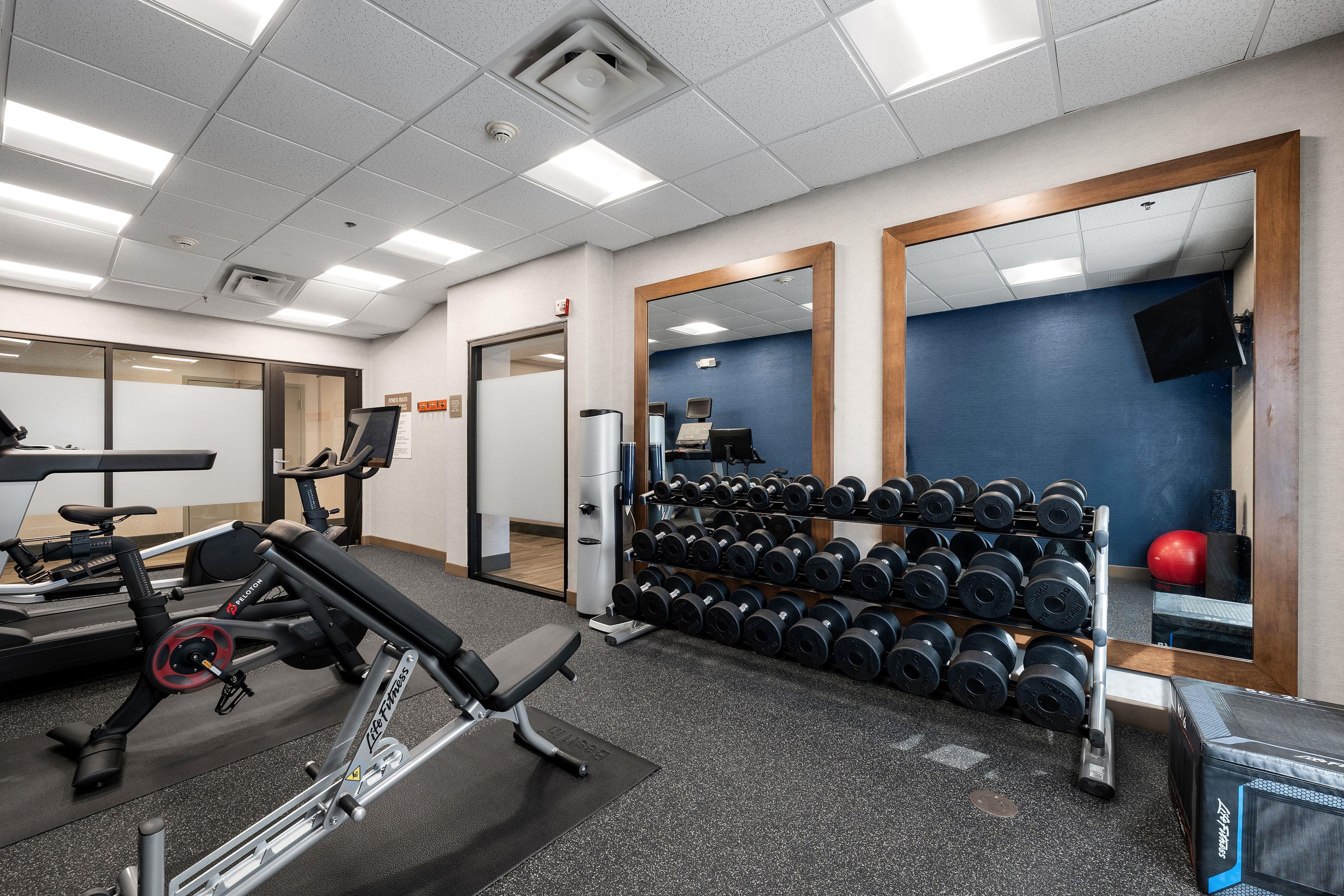 A gym with exercise equipment, a mirror, and a wall-mounted television.