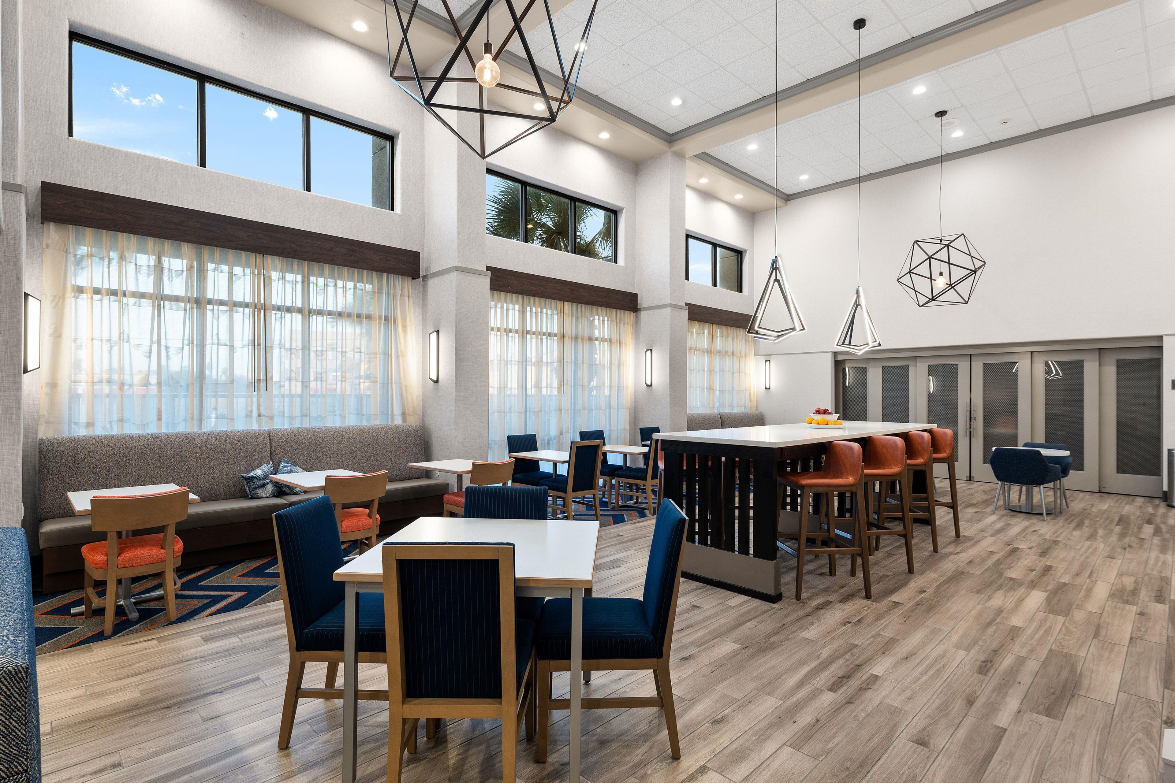 A modern dining area with high ceilings, large windows, and contemporary furniture.