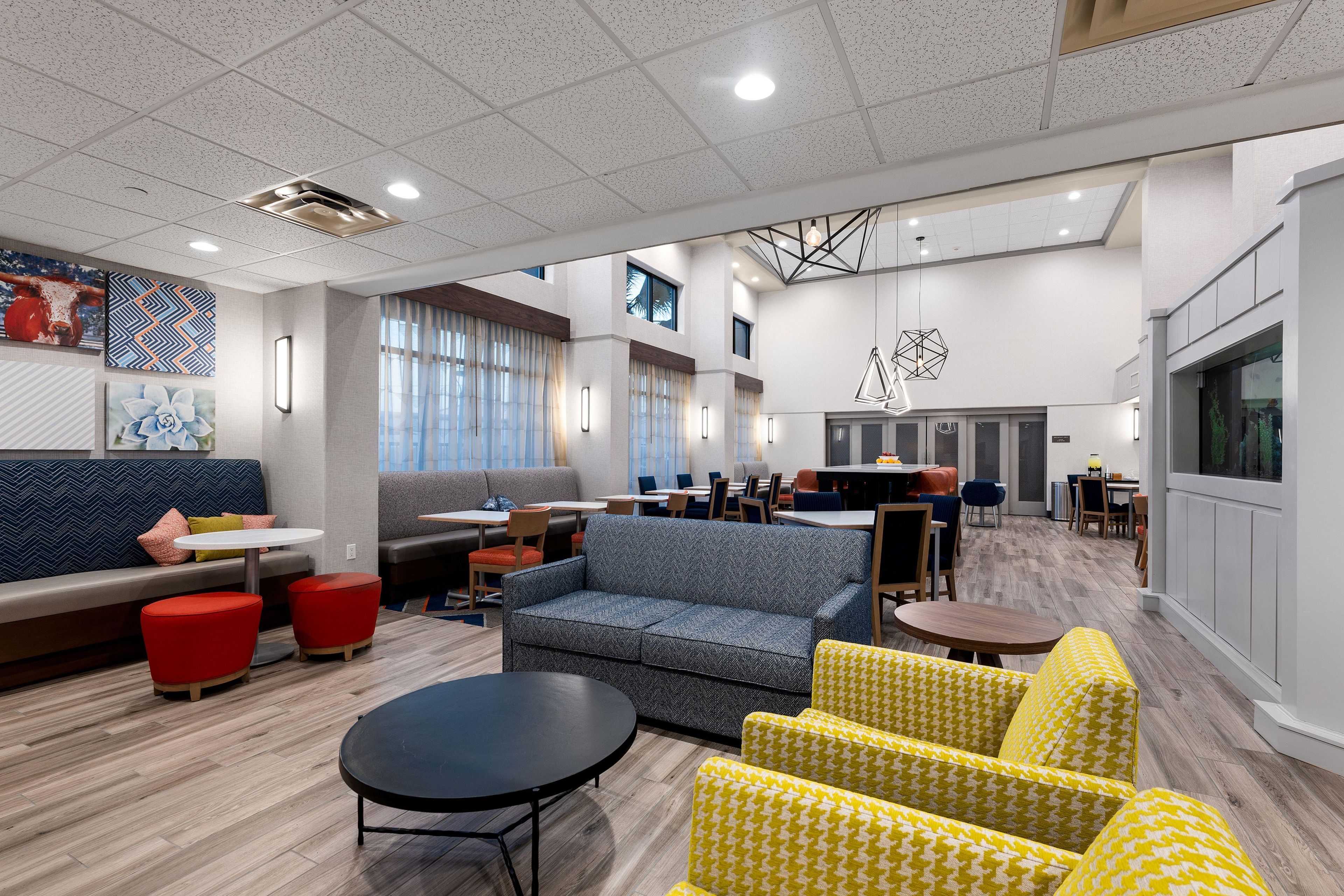 A spacious lounge area with seating arrangements, a dining area, and a modern ceiling design.