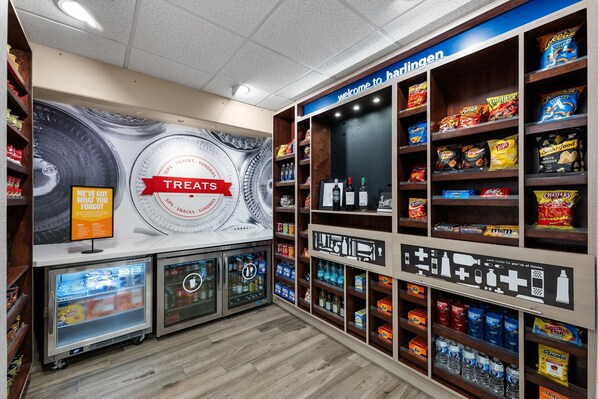 Un supermercado con una sección etiquetada 'TREATS' y estantes llenos de aperitivos y bebidas.