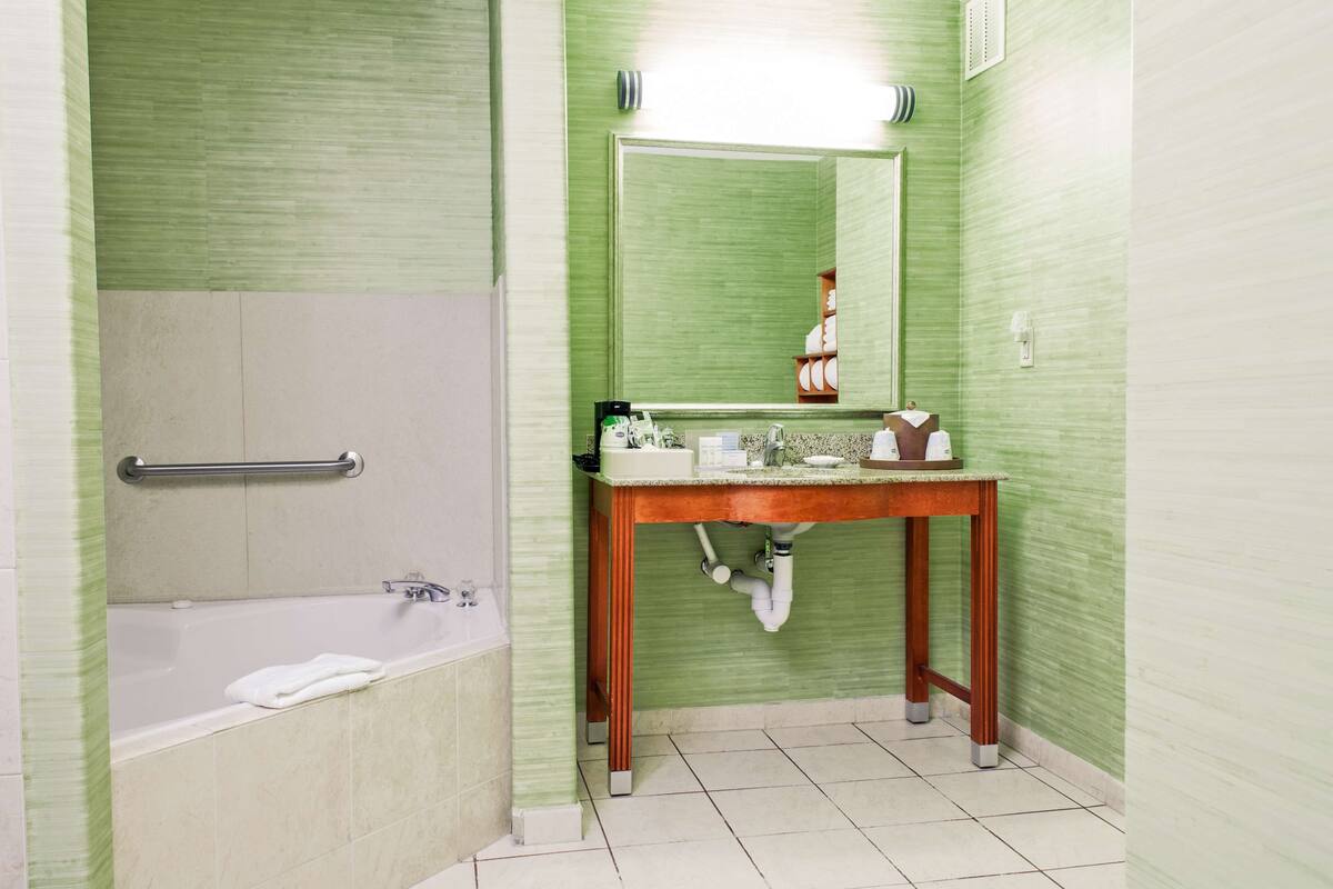 A bathroom with a bathtub, a wooden vanity, a mirror, and a towel rack.