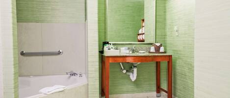 Un baño con bañera, tocador de madera, espejo y toallero.