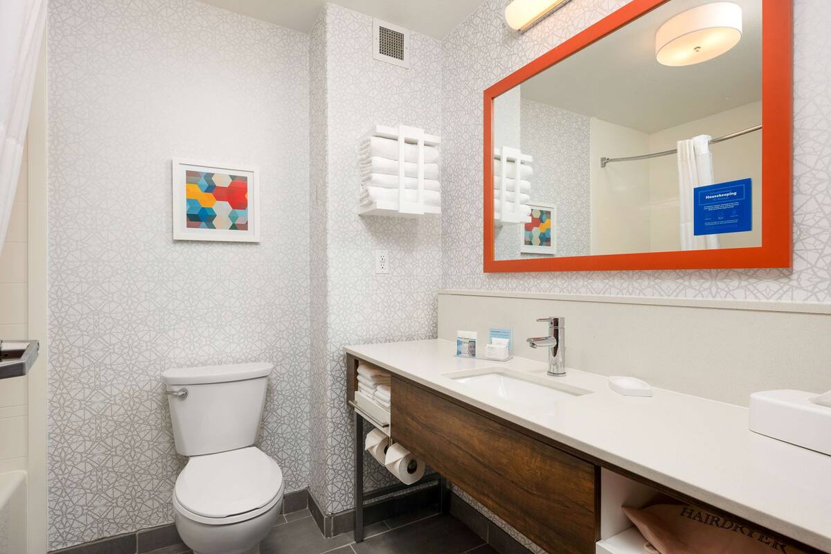 A modern bathroom with a toilet, sink, and mirror.