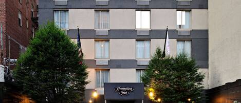A multi-story hotel with a flat facade, large windows, and a sign indicating it is the Hampton Inn.