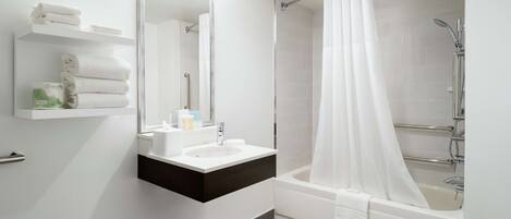 A modern bathroom with a white sink, mirror, and shower.