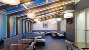 A modern restaurant with high ceilings, skylights, and a mix of booth and table seating. - Hampton Inn Manhattan-Chelsea (New York)