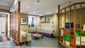 A modern living room with a sofa, coffee table, and decorative plants. - Hampton Inn Manhattan-Chelsea (New York)