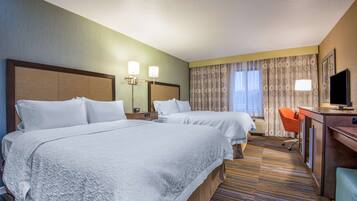 A hotel room with two beds, a desk with a TV, a chair, and a large window with curtains.