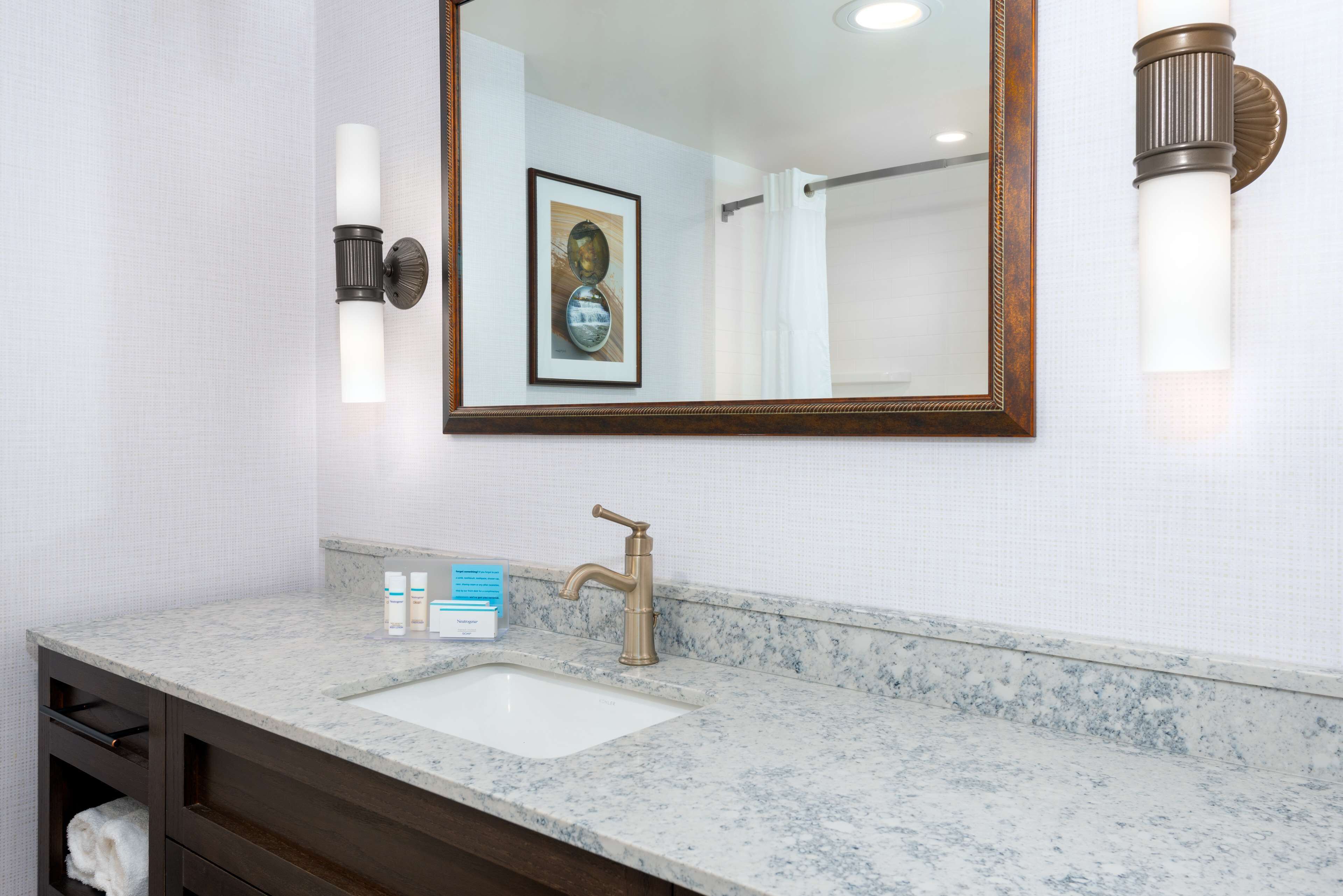A bathroom with a marble sink, a framed mirror, and a framed picture on the wall.