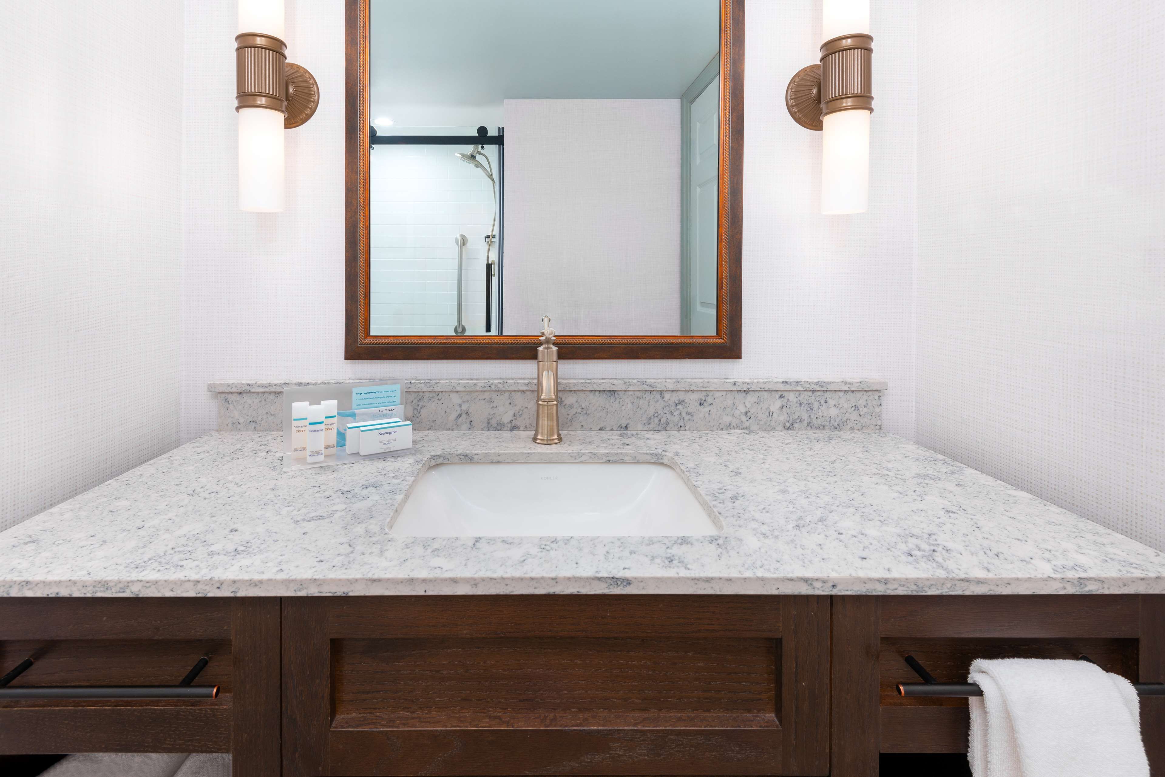 Une salle de bain avec un lavabo en marbre, un meuble-lavabo en bois et un grand miroir.