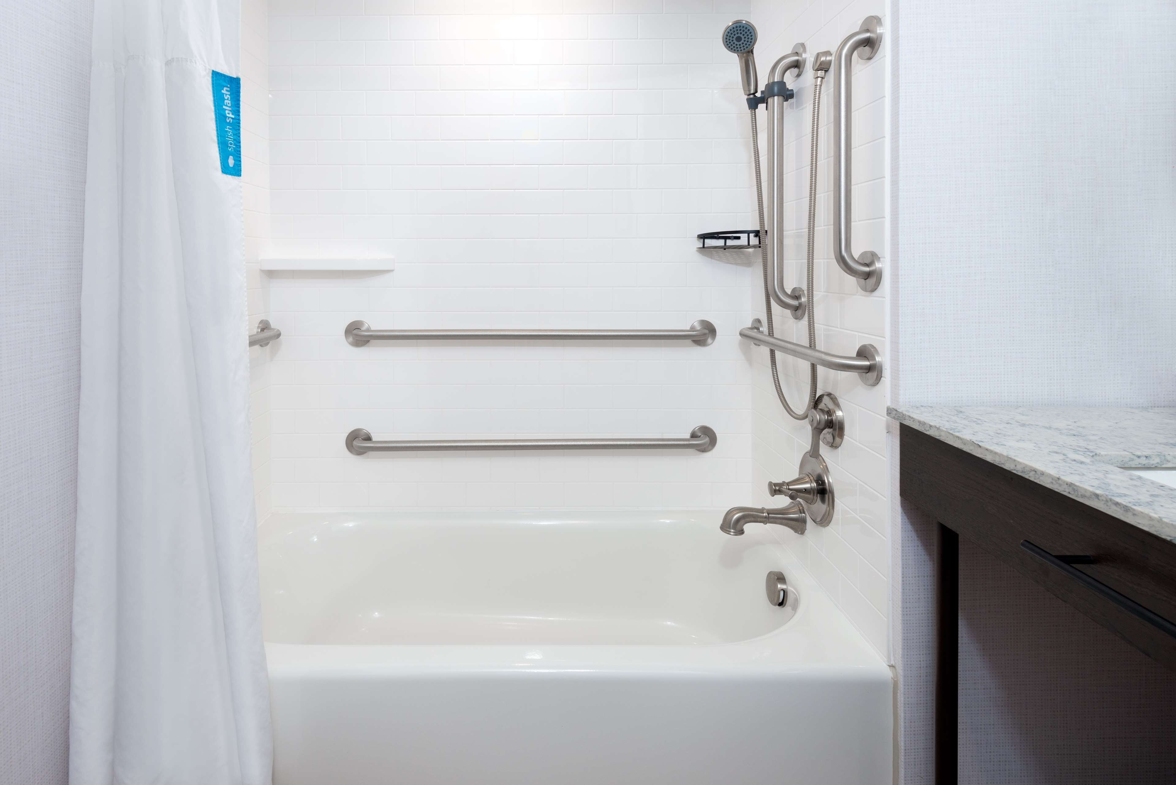 A white bathtub with grab bars and a showerhead.