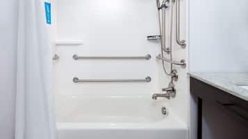 A white bathtub with grab bars and a showerhead.