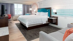 Een moderne hotelkamer met een groot bed, een bureau, een televisie en uitzicht op het landschap.