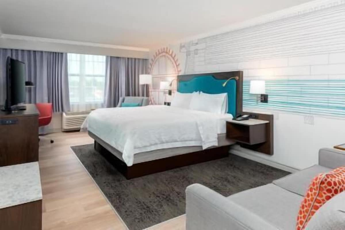 Una habitación de hotel con cama, escritorio, silla y sofá.