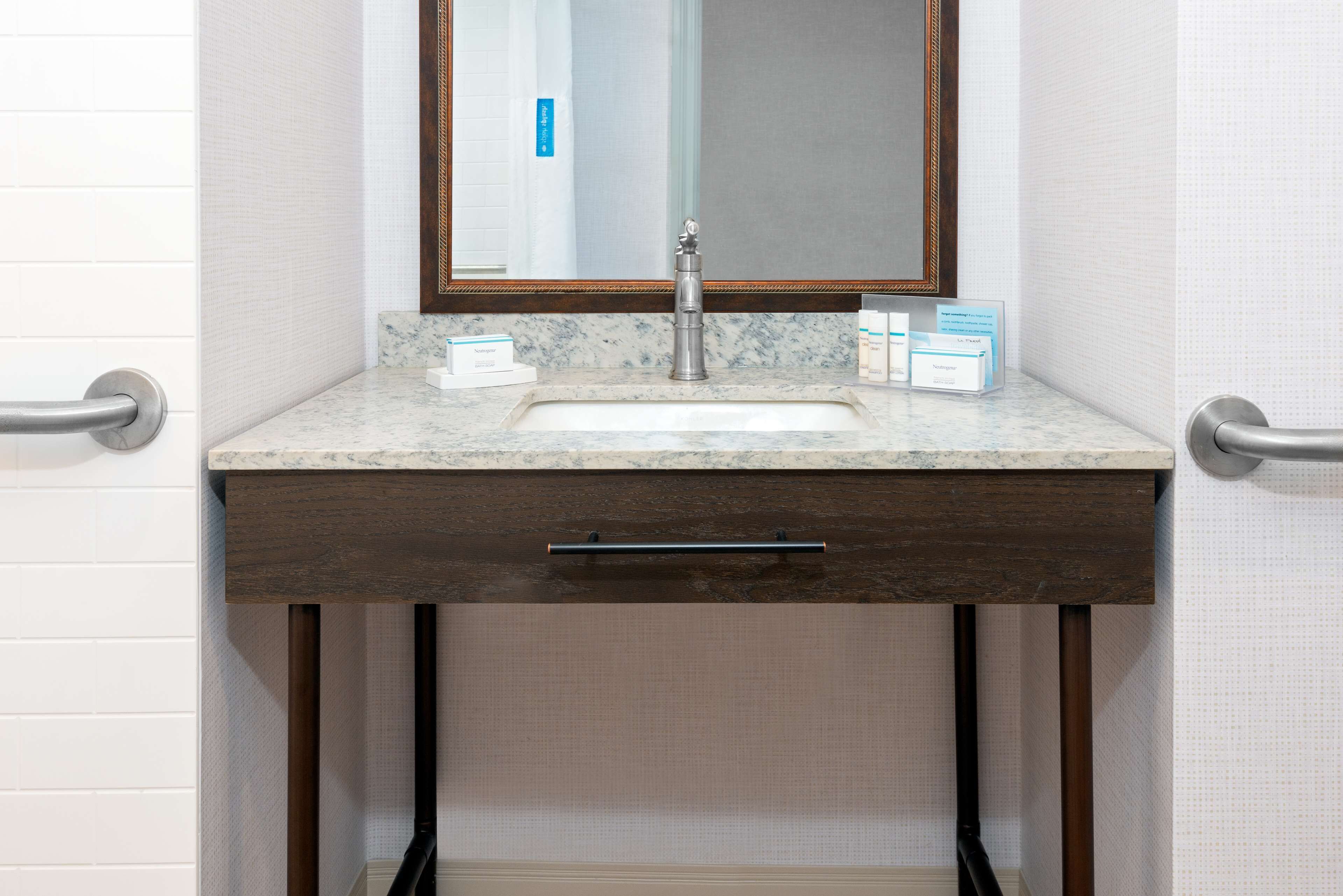 A bathroom with a marble sink, wooden vanity, and a mirror with a wooden frame.