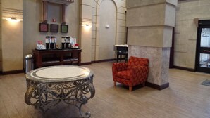 A lobby with a marble table, a red armchair, a statue, and a coffee station. - Hampton Inn Bowling Green (Bowling Green)