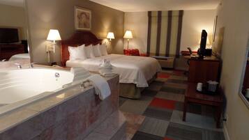 A hotel room with a large bathroom, a bed with white linens, two bedside lamps, a flat-screen TV, and a check-in counter.