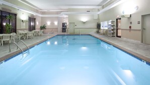 An indoor swimming pool with clear water, surrounded by lounge chairs and a reception area with a counter and chairs. - Hampton Inn Bowling Green (Bowling Green)