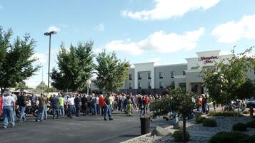 A crowded outdoor area with a Hampton Inn hotel in the background.